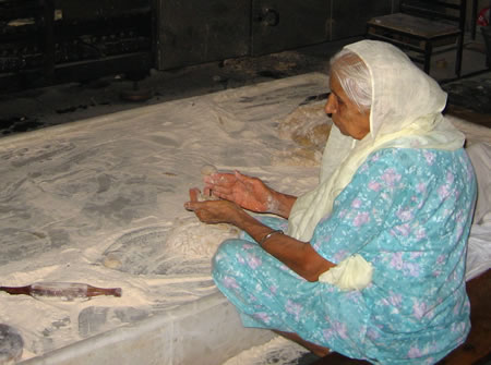 Woman making roti in Sikh temple, India