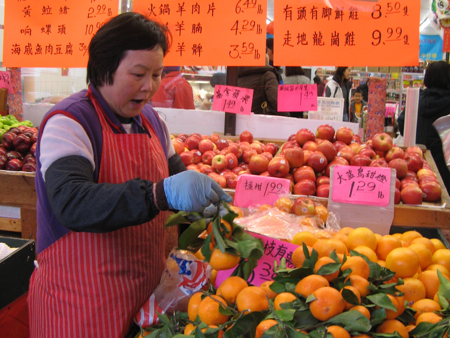 Shopkeeper with oranges, Chinatown Supermarket, Vancouver