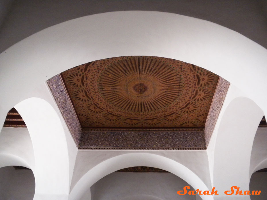 Arches surround a painted ceiling panel in Marrakesh