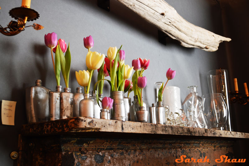 Silvered bottles and tulips create a beautiful mantle at the Antique and Garden Fair in Chicago