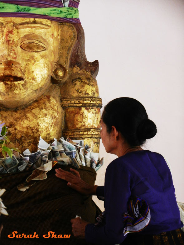 Offering money and gold leaf to a Nat in Bagan, Myanmar