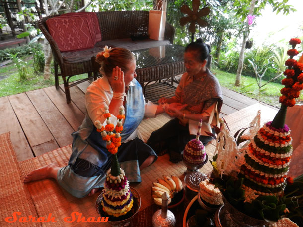 My cultural guide ties my strings on during my baci ceremony in Laos