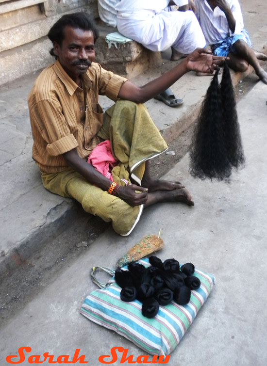 A man sells hair to be used as an offering outside a temple in Tamil Nadu, India