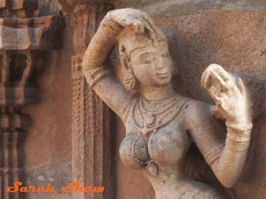 A woman grooms herself in stone at a temple in Tamil Nadu, India