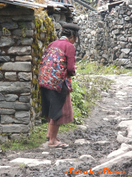 Brokpa woman navigates a rain soaked path with her traditional hat