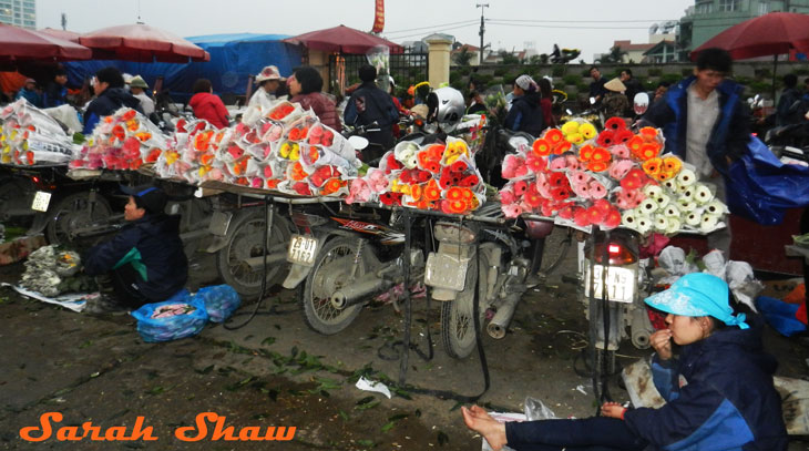 Flower vendors display their items on the back of scooters at the Hanoi Flower Market, Vietnam