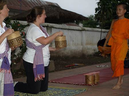 Tourists Giving Alms to Monks